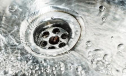 Stainless steel sink plug hole close up with water